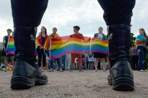 militaire en bottes face à des manifestants avec bannière LGBT