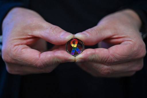 Mains tenant un m&eacute;daillon VIH aux couleurs de l'arc-en-ciel